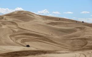 picture of dunes with several ATV’s buzzing around